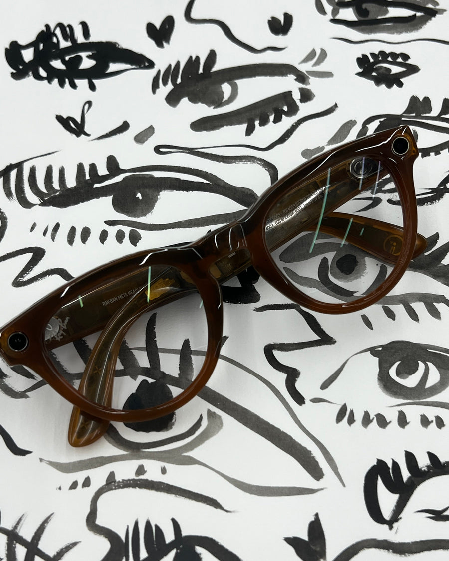 rayban meta glasses with clear lenses, resting on a white background printed with black hand-drawn eyes. custom illustration for store display